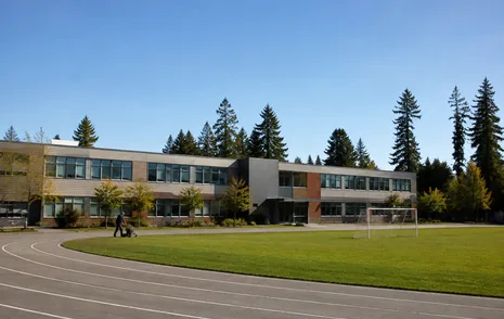 A secondary school building and playing field on a clear day in a Surrey BC neighbourhood