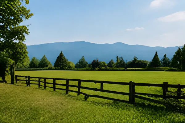 A post and rail fence along an open green field with hills behind, homes for sale in Aldergrove, Langley BC